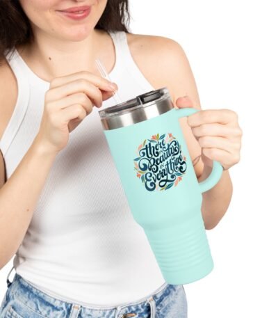 A woman holding a mint green 40oz Insulated Travel Mug featuring the floral lettering "There is Beauty in Everything" while using a straw.