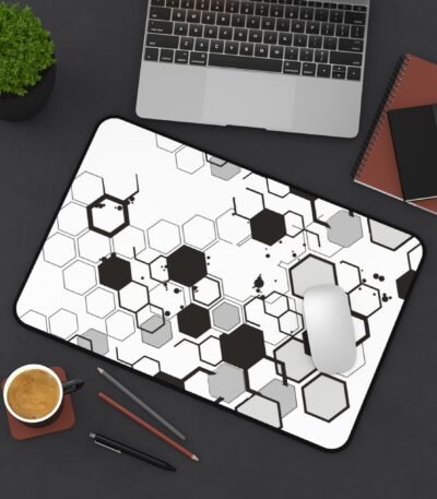 A monochrome Hex Grid Desk Mat featuring a black and white geometric hexagon pattern on a dark office desk with a laptop and mouse.