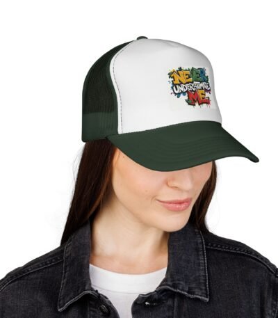 A woman wearing a dark green and white Never Underestimate Me Trucker Hat featuring a vibrant graffiti-style print on the white foam front and a dark green visor.