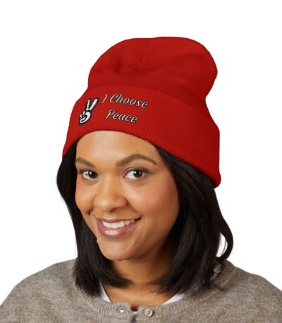 A woman wearing a vibrant red Embroidered Peace Logo Cuffed Beanie featuring a white peace sign and the text "I Choose Peace" embroidered on the front.